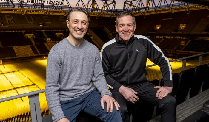 Zwei Männer die nebeneinander stehen und in die Kamera lächeln 