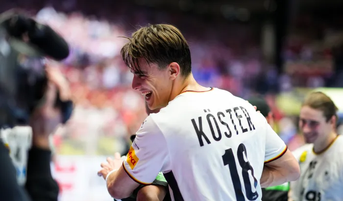 Ein junger Mann im Deutschland Trikot der lachend jemanden umarmt. 