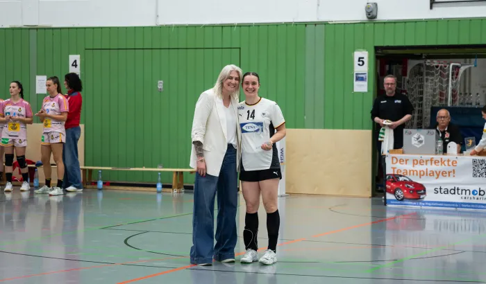 Zwei Frauen die in die Kamera lächeln und einen Pokal in den Händen halten