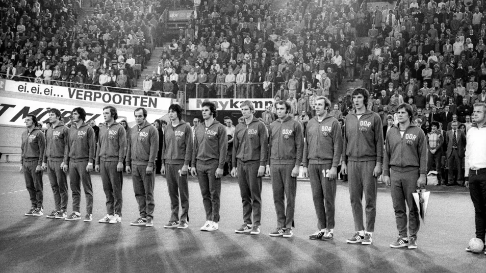 Ein schwarz-weiß-Foto der DDR-Handballnationalmannschaft der Männer, in einer Handballarena. 