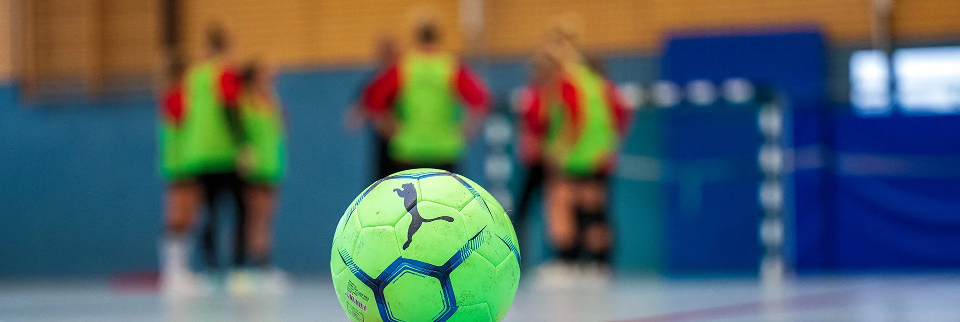 Ball im Fokus, dahinter eine Trainingsgruppe