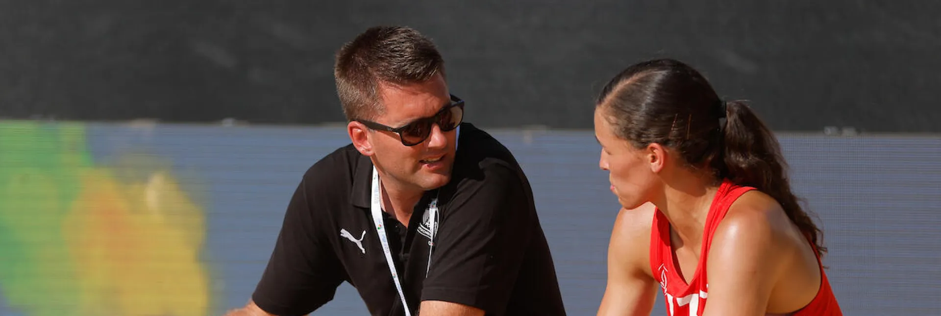 Beachhandballtrainer tauscht sich mit einer Spielerin aus