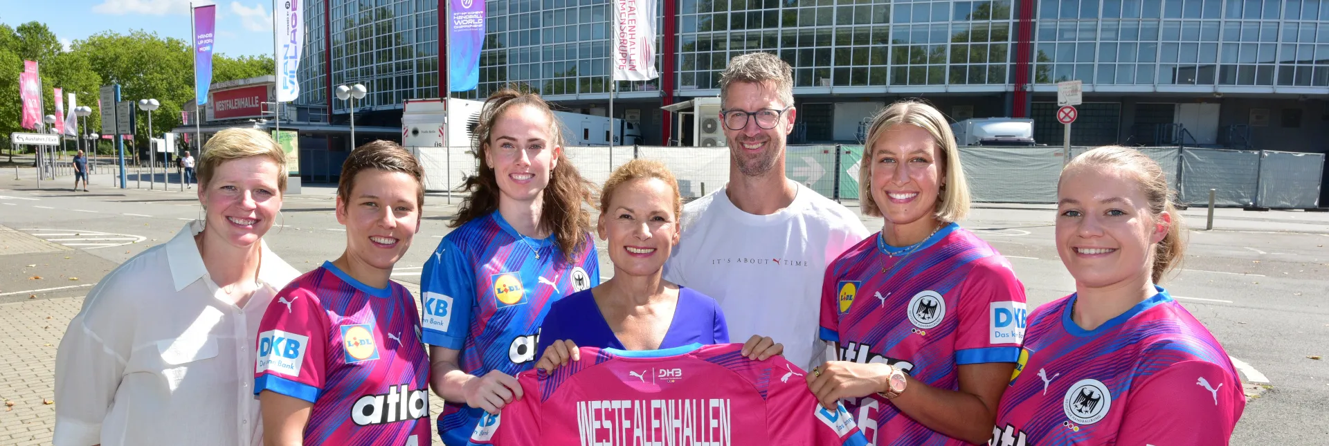 Spielerinnen der Nationalmannschaft, Bundestrainer Markus Gaugisch, Clara Woltering und Sabine Loos posieren vor der Westfalenhalle mit Trikot.