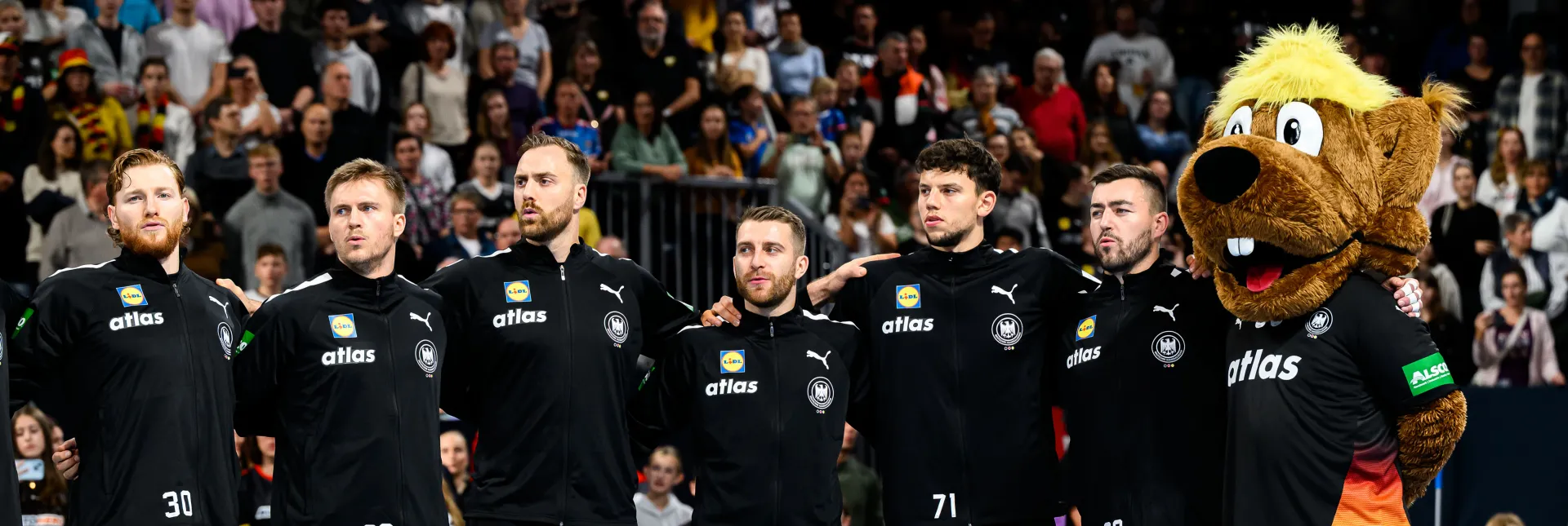 Männer-Nationalmannschaft Handball bei der Hymne mit Maskottchen.