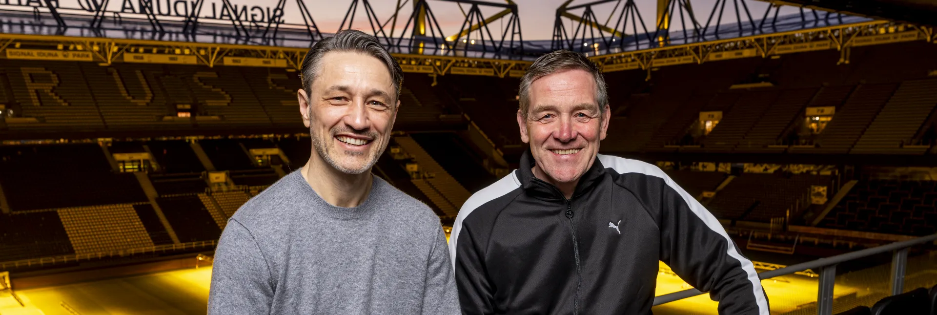 Zwei Männer die nebeneinander stehen und in die Kamera lächeln 