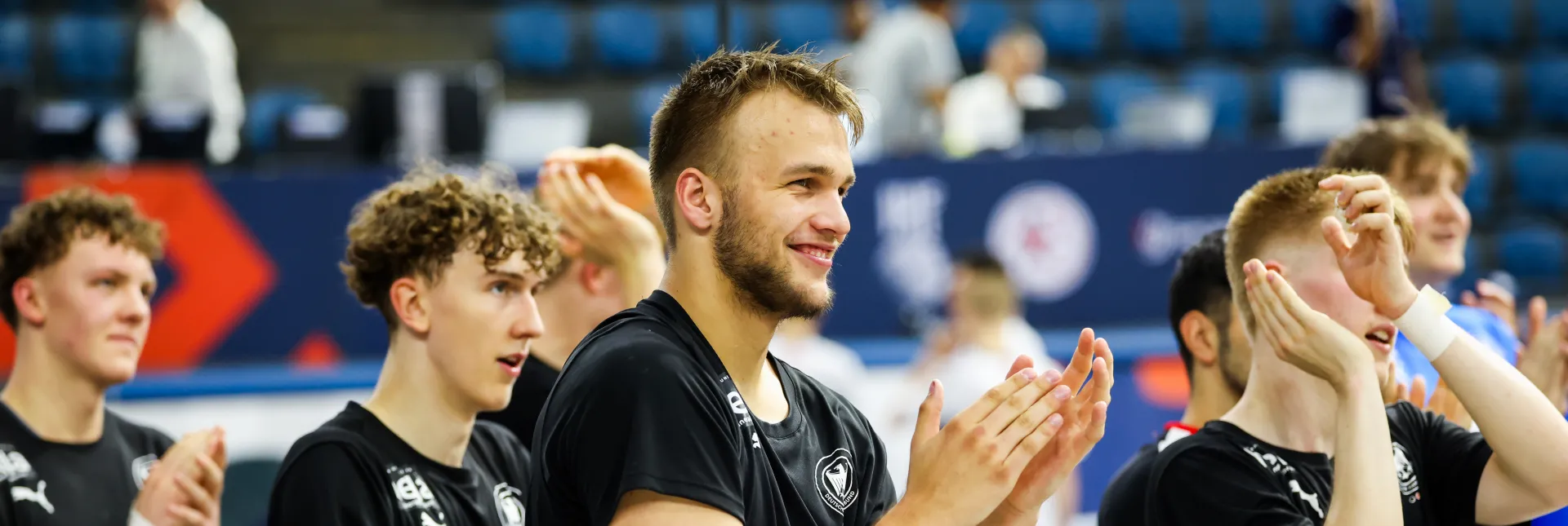 Eine Truppe von Männern in schwarzen Trikots die jubeln und klatschen