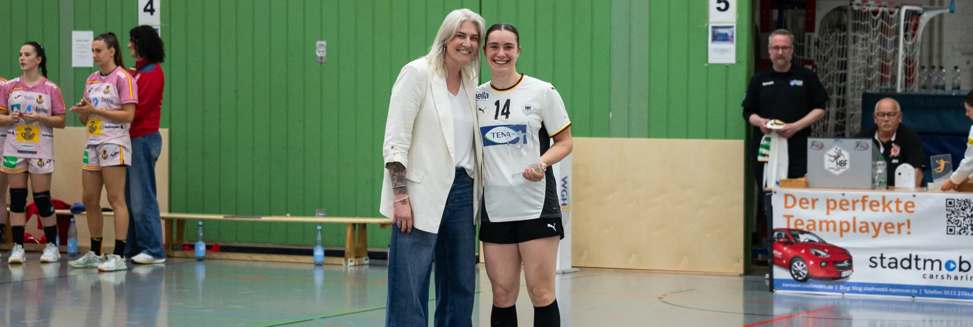 Zwei Frauen die in die Kamera lächeln und einen Pokal in den Händen halten