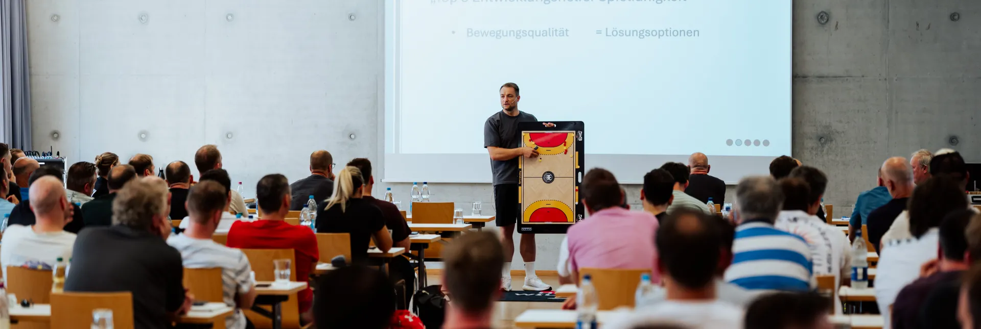 Eine Versammlung von Menschen die sich einen Vortrag anhören.