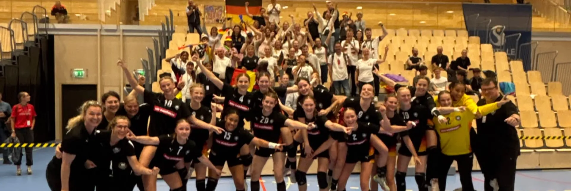 Eine Truppe von Mädels in Hnandballsachen, die zusammenstehen mit den armen ineinander verschlungen.. 