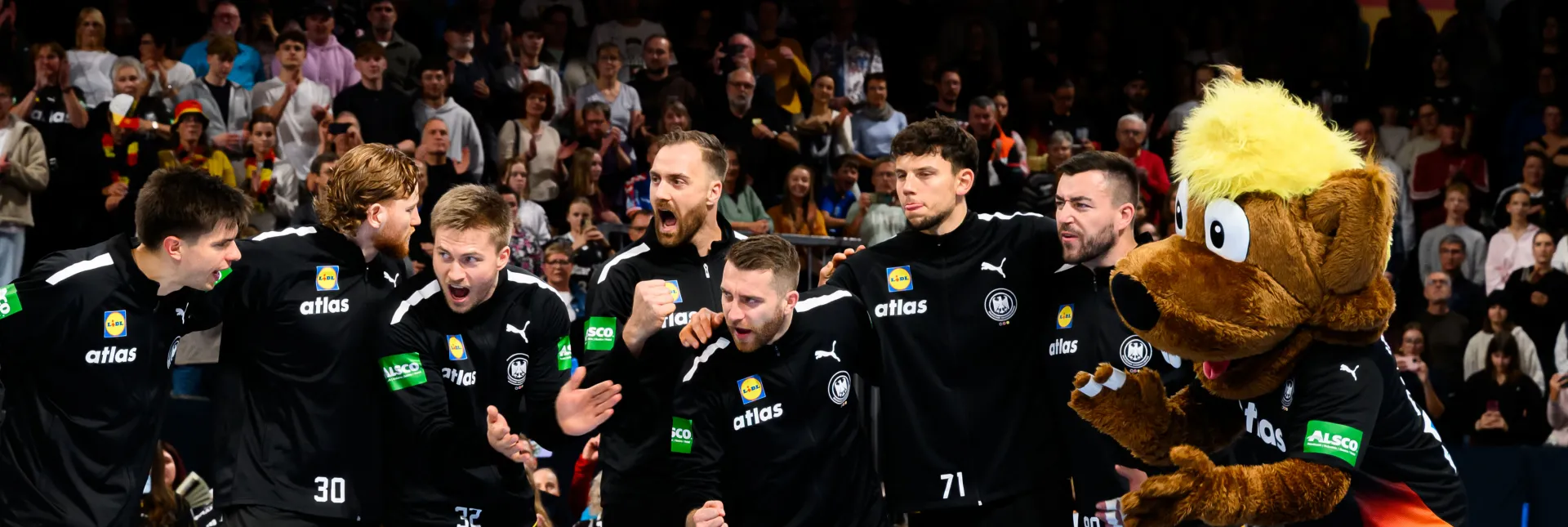 Deutsche Handball-Männer-Nationalmannschaft steht zusammen in einer Reihe und jubelt sich zu.