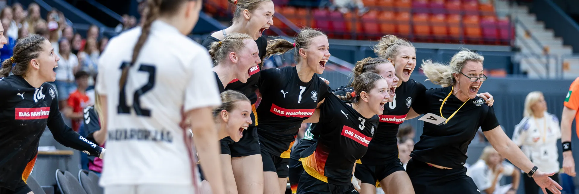Eine Handballmannschaft die sich freut und zusammen jubelt.