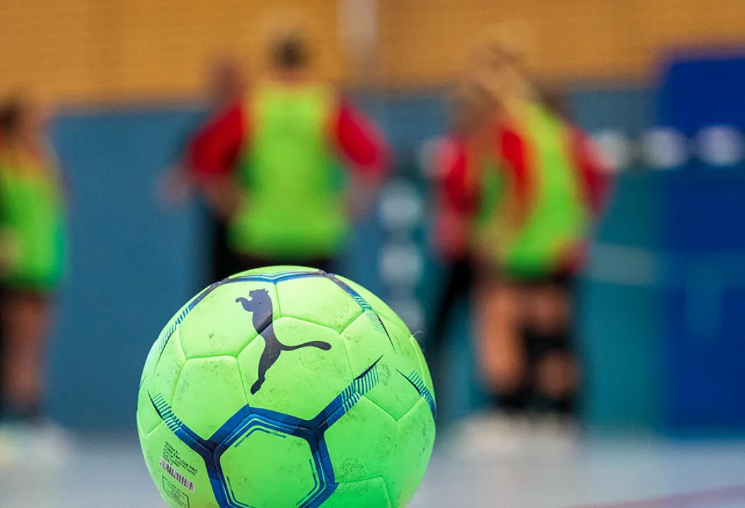 Ball im Fokus, dahinter eine Trainingsgruppe