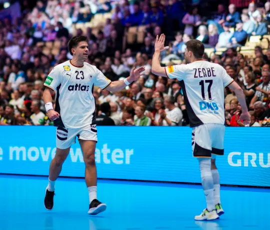 Renards Uscins und Lukas Zerbe beim Abklatschen während eines Handballspiels.