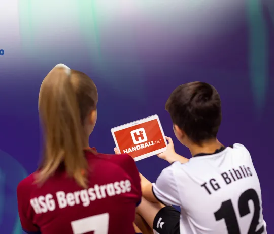 Zwei Handballer/innen blicken auf das neue handball.net