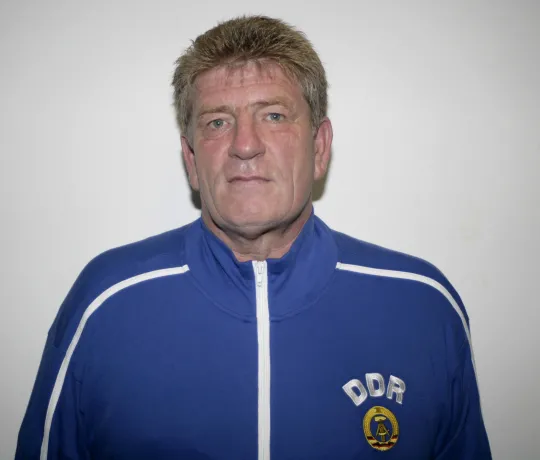 Ein Porträtfoto eines Mannes in blauer Jacke mit DDR auf der Brust