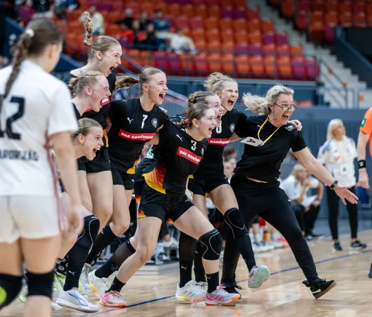 Eine Handballmannschaft die sich freut und zusammen jubelt.