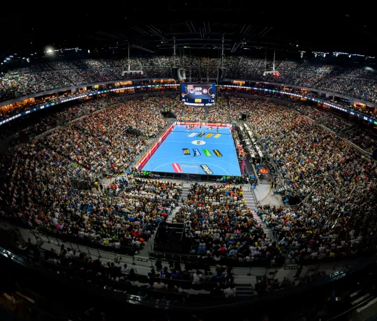 Blick von oben in den gefüllten Innenraum der Lanxess arena bei einem Handballspiel.