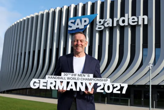 Alfred Gislason mit Schriftzug in der Hand draußen vor den SAP Garden.