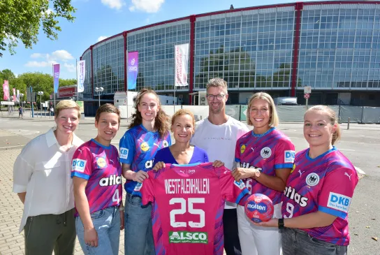 Spielerinnen der Nationalmannschaft, Bundestrainer Markus Gaugisch, Clara Woltering und Sabine Loos posieren vor der Westfalenhalle mit Trikot.