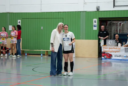 Zwei Frauen die in die Kamera lächeln und einen Pokal in den Händen halten