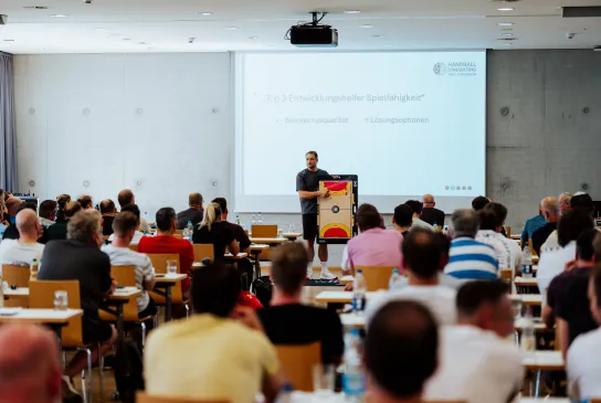 Eine Versammlung von Menschen die sich einen Vortrag anhören.