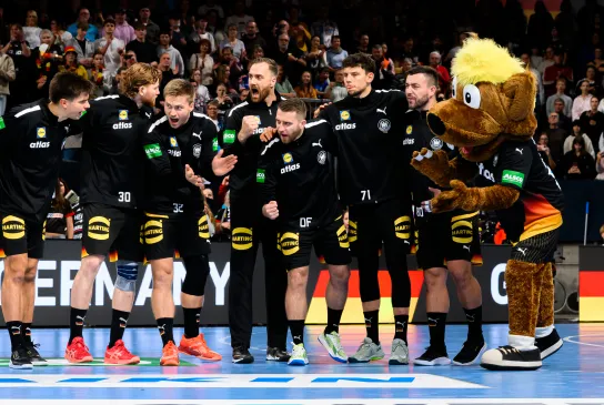 Deutsche Handball-Männer-Nationalmannschaft steht zusammen in einer Reihe und jubelt sich zu.